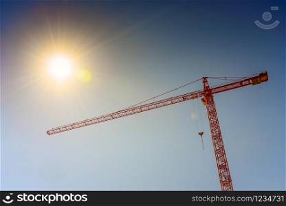 Industrial crane and sun on blue sky background