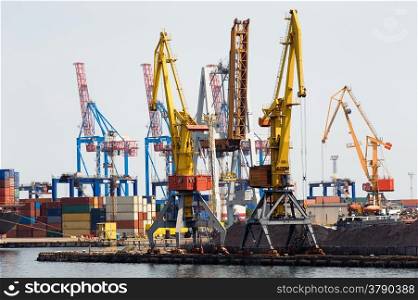 Industrial cranes and cargo on a quay in a docks waiting to be loaded onto ships for transport to overseas destinations