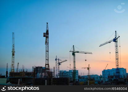 Industrial cranes. Industrial landscape with silhouettes of constraction cranes on dramatic sunset background