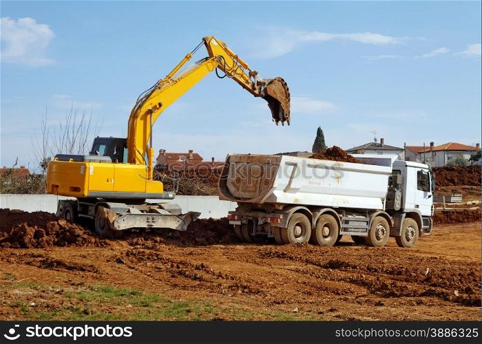 industrial excavator loading tipper truck on construction site