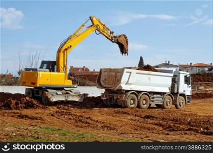 industrial excavator loading tipper truck on construction site