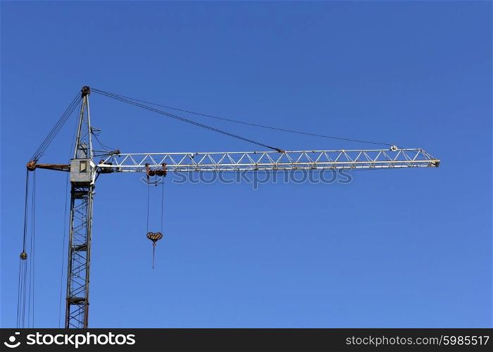 Industrial landscape, building crane against the blue sky.