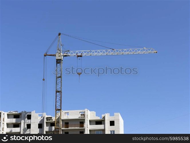 Industrial landscape, building crane against the blue sky.