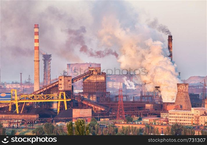 Industrial landscape in Ukraine. Steel factory at sunset. Pipes with smoke. Metallurgical plant. steelworks, iron works. Heavy industry in Europe. Air pollution from smokestacks, ecology problems.