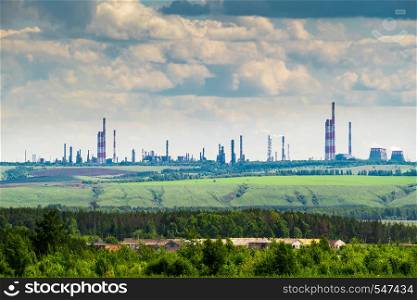 Industrial landscape with an oil refinery on the green hill.. Industrial landscape with an oil refinery on the green hill