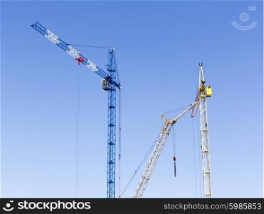 Industrial landscape with silhouettes of cranes on the sky background