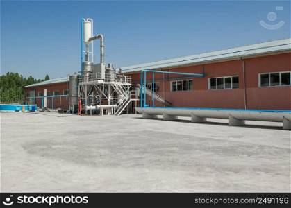 industrial one-story building with tanks and irrigation ditch. storage tank and building