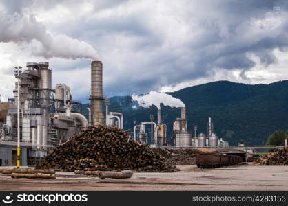 Industrial plant of a furniture factory with smoking chimneys on stormy sky