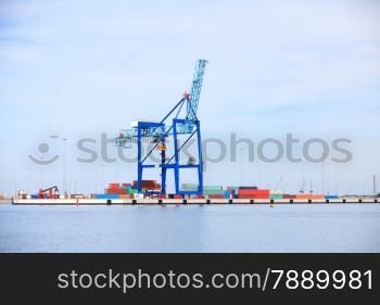 Industrial port cargo crane and containers loading and unloading over blue sky background