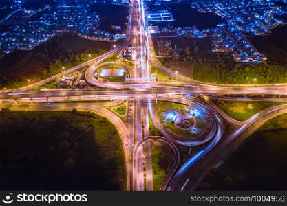 industrial ring road traffic car and motorway highway expressway in night time and lighting over colourful aerial top view from drone