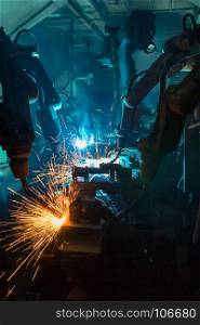 Industrial robots are welding in car factory