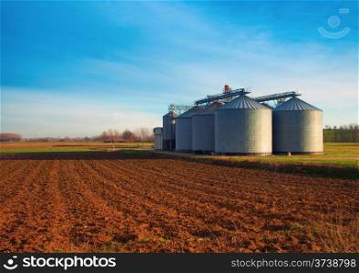 Industrial silos in the fields, in the sunset