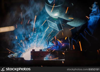 Industrial worker is welding assembly part in car factory