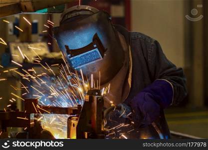 industrial worker is  welding car part in factory