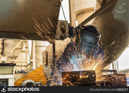 Industrial worker is welding car part in factory