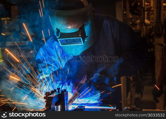 Industrial worker is welding in factory