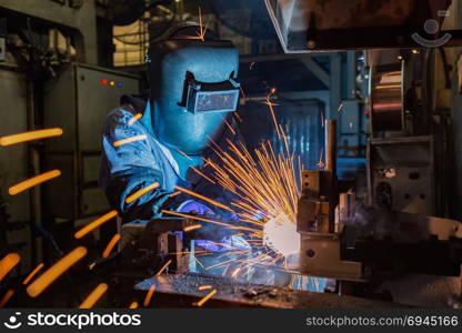 Industrial worker is welding in factory