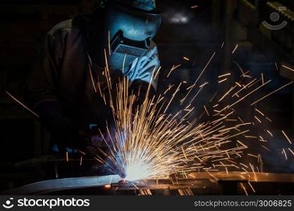 Industrial worker is welding in factory with protective mask