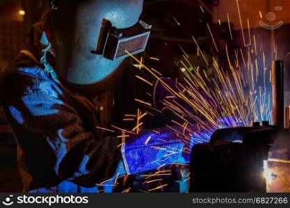Industrial worker is welding metal part