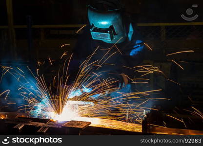 Industrial worker with protective mask is welding metal .