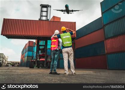 Industrial worker works with co-worker at overseas shipping container port . Logistics supply chain management and international goods export concept .. Industrial worker works with co-worker at overseas shipping container port