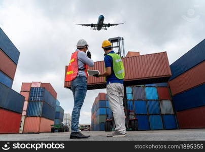 Industrial worker works with co-worker at overseas shipping container port . Logistics supply chain management and international goods export concept .. Industrial worker works with co-worker at overseas shipping container port