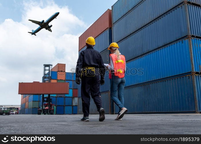 Industrial worker works with co-worker at overseas shipping container port . Logistics supply chain management and international goods export concept .. Industrial worker works with co-worker at overseas shipping container port