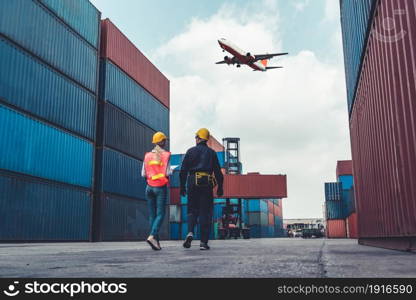 Industrial worker works with co-worker at overseas shipping container port . Logistics supply chain management and international goods export concept .. Industrial worker works with co-worker at overseas shipping container port