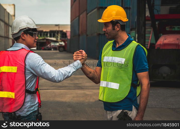 Industrial worker works with co-worker at overseas shipping container yard . Logistics supply chain management and international goods export concept .. Industrial worker works with co-worker at overseas shipping container yard