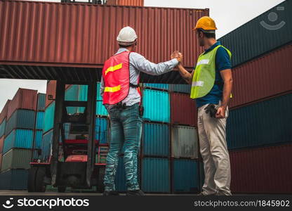 Industrial worker works with co-worker at overseas shipping container yard . Logistics supply chain management and international goods export concept .. Industrial worker works with co-worker at overseas shipping container yard