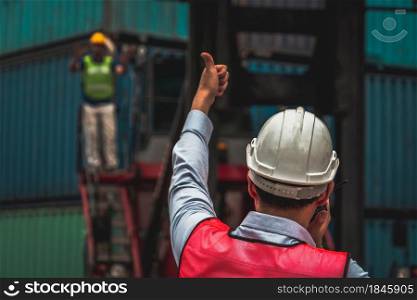 Industrial worker works with co-worker at overseas shipping container yard . Logistics supply chain management and international goods export concept .. Industrial worker works with co-worker at overseas shipping container yard