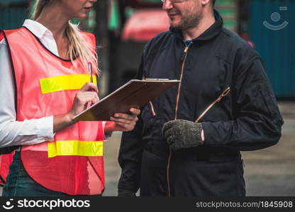 Industrial worker works with co-worker at overseas shipping container yard . Logistics supply chain management and international goods export concept .. Industrial worker works with co-worker at overseas shipping container yard