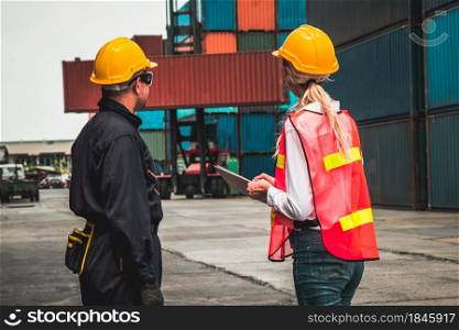 Industrial worker works with co-worker at overseas shipping container yard . Logistics supply chain management and international goods export concept .. Industrial worker works with co-worker at overseas shipping container yard