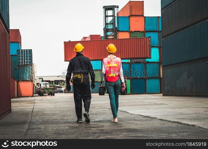 Industrial worker works with co-worker at overseas shipping container yard . Logistics supply chain management and international goods export concept .. Industrial worker works with co-worker at overseas shipping container yard