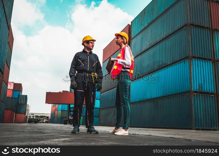 Industrial worker works with co-worker at overseas shipping container yard . Logistics supply chain management and international goods export concept .. Industrial worker works with co-worker at overseas shipping container yard