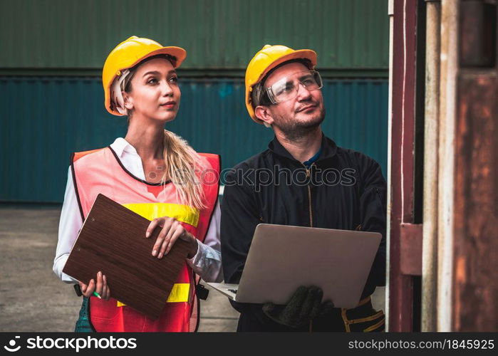 Industrial worker works with co-worker at overseas shipping container yard . Logistics supply chain management and international goods export concept .. Industrial worker works with co-worker at overseas shipping container yard