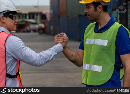 Industrial worker works with co-worker at overseas shipping container yard . Logistics supply chain management and international goods export concept .. Industrial worker works with co-worker at overseas shipping container yard