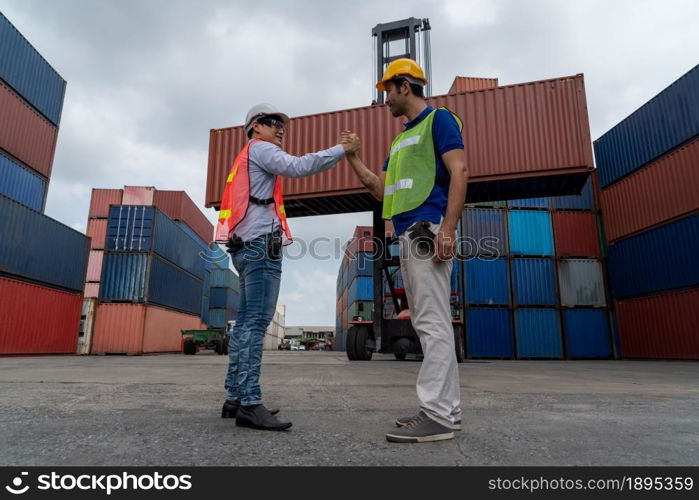 Industrial worker works with co-worker at overseas shipping container yard . Logistics supply chain management and international goods export concept .. Industrial worker works with co-worker at overseas shipping container yard