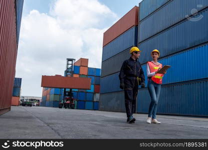 Industrial worker works with co-worker at overseas shipping container yard . Logistics supply chain management and international goods export concept .. Industrial worker works with co-worker at overseas shipping container yard