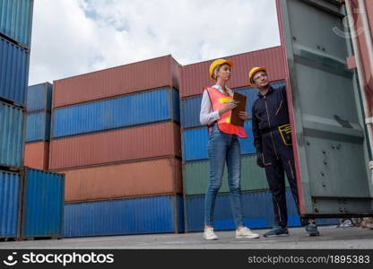 Industrial worker works with co-worker at overseas shipping container yard . Logistics supply chain management and international goods export concept .. Industrial worker works with co-worker at overseas shipping container yard