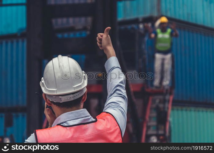 Industrial worker works with co-worker at overseas shipping container yard . Logistics supply chain management and international goods export concept .. Industrial worker works with co-worker at overseas shipping container yard