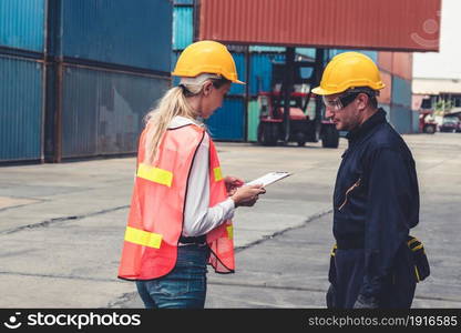 Industrial worker works with co-worker at overseas shipping container yard . Logistics supply chain management and international goods export concept .. Industrial worker works with co-worker at overseas shipping container yard