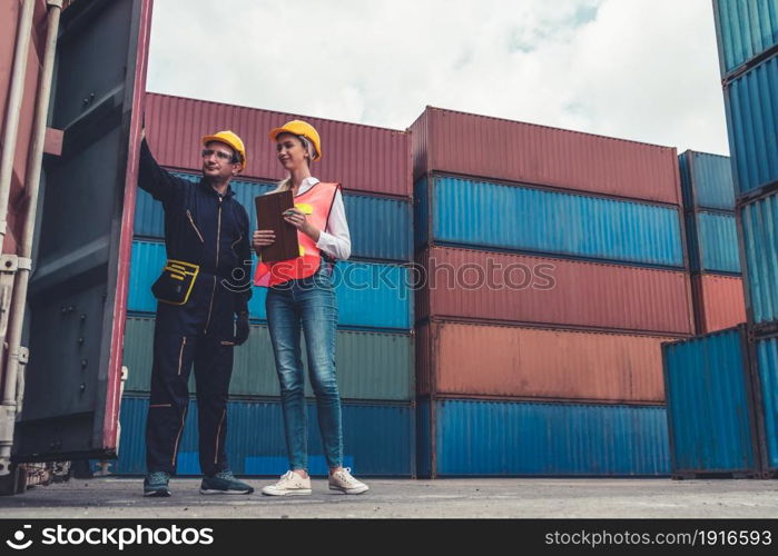 Industrial worker works with co-worker at overseas shipping container yard . Logistics supply chain management and international goods export concept .. Industrial worker works with co-worker at overseas shipping container yard