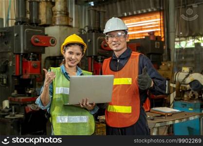 Industrial workers learning work instructions holding laptop computer at factory.