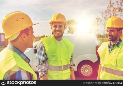 industry, building, construction and people concept - happy male builders in high visible vests outdoors