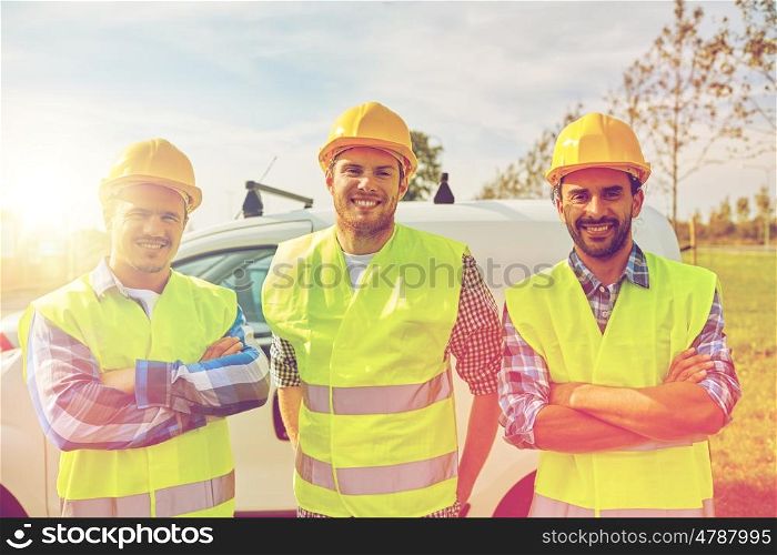industry, building, construction and people concept - happy male builders in high visible vests outdoors