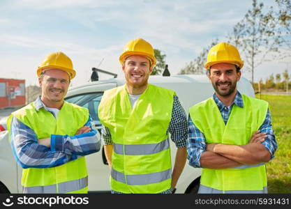 industry, building, construction and people concept - happy male builders in high visible vests outdoors