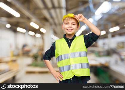 industry, manufacture and profession concept - happy smiling little boy in protective helmet and safety vest over workshop background. little boy in protective helmet and safety vest