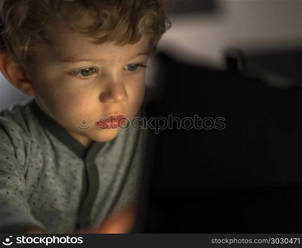 infant boy watching an tablet. beautiful baby boy on the bed watching a tablet,computer, close-up.