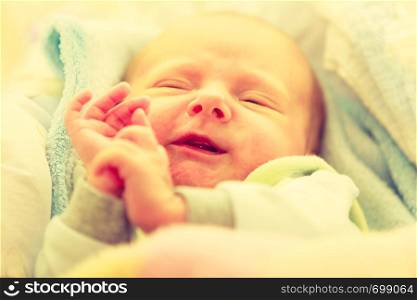 Infant care, beauty of childhood concept. Little newborn baby sleeping calmly in bed surrounded with blankets making funny faces.. Little newborn baby sleeping calmly in blanket